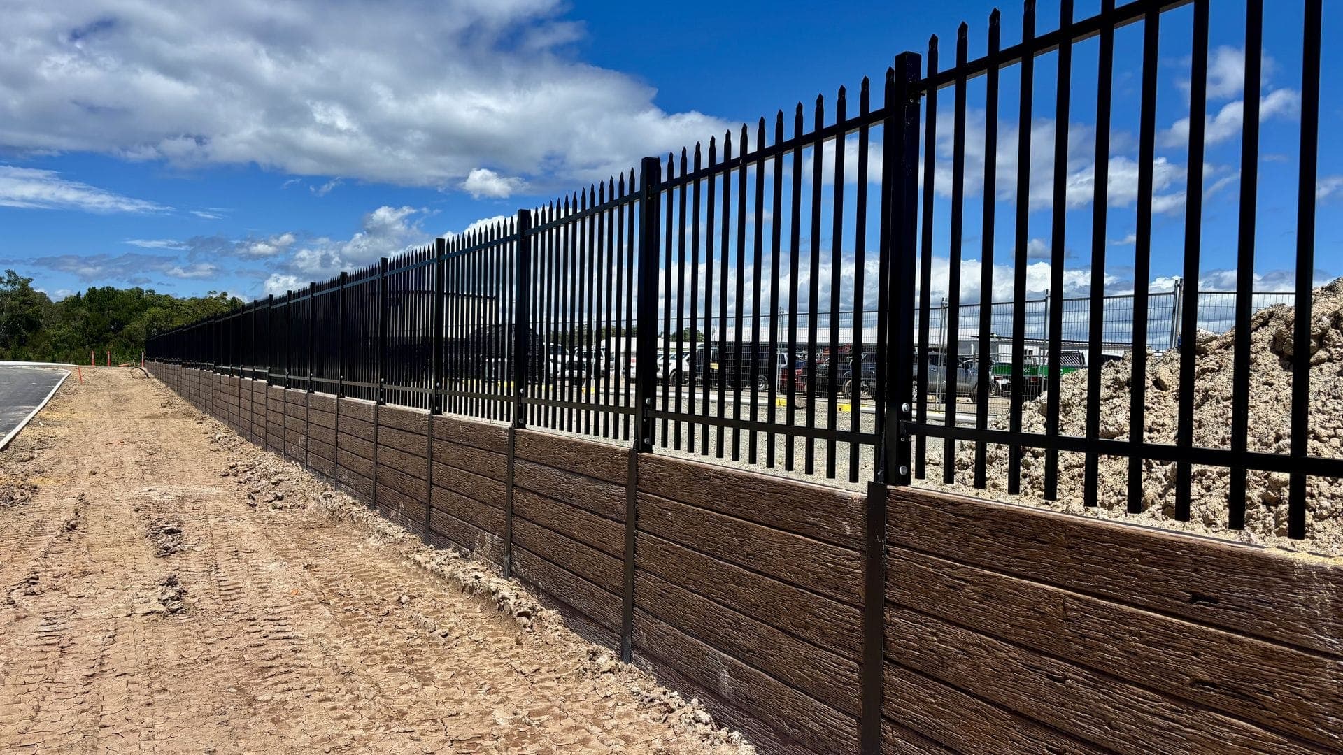 Black palisade fencing on timber sleeper retaining wall