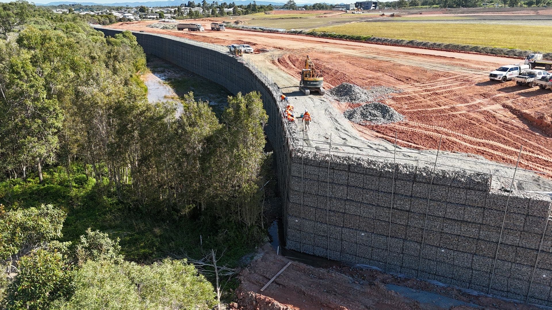 Massive gabion retaining wall aerial view with red earth and bushland
