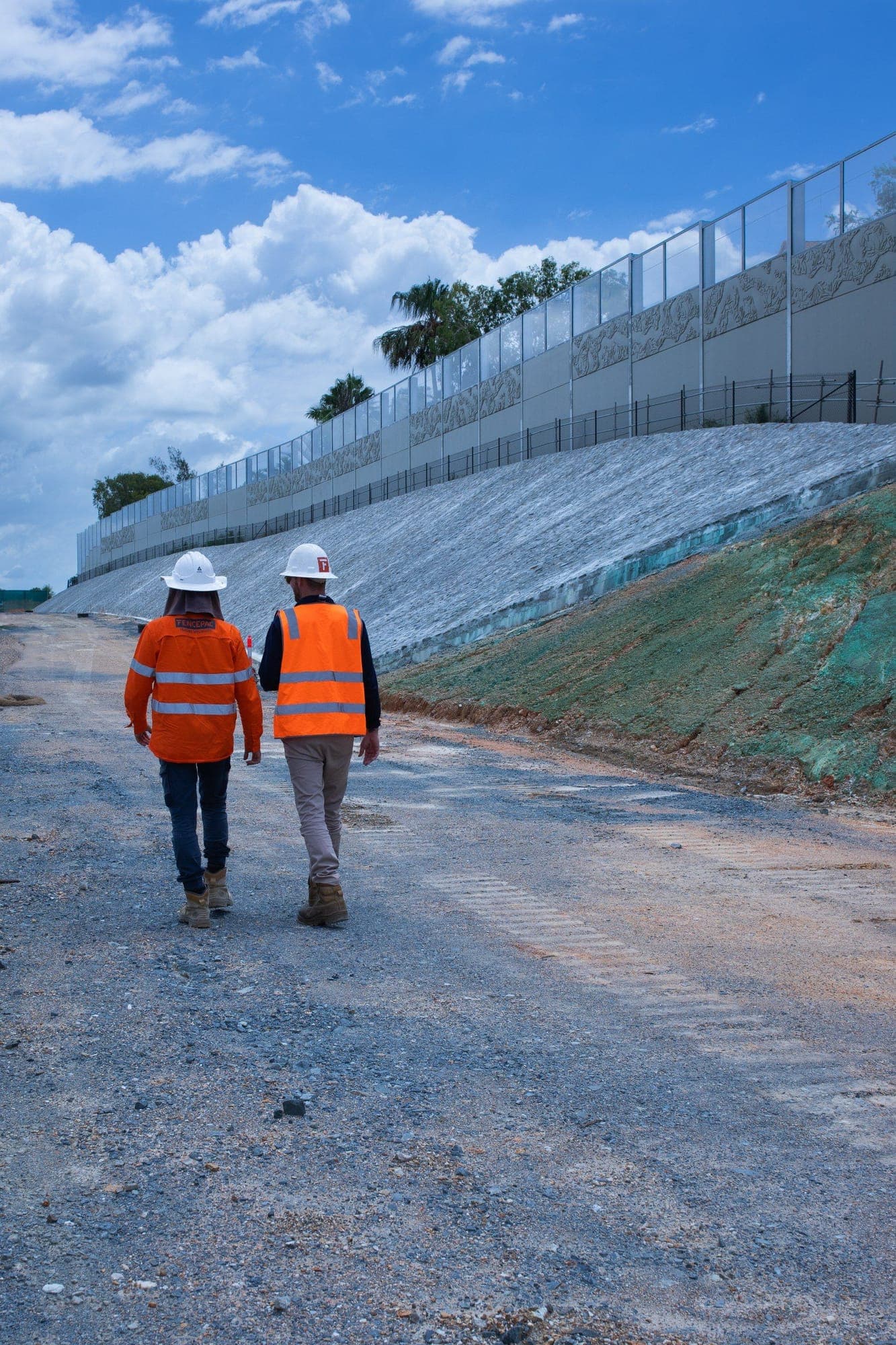 Fencepac crew walking alongside decorative barrier with stone pitching and glass top