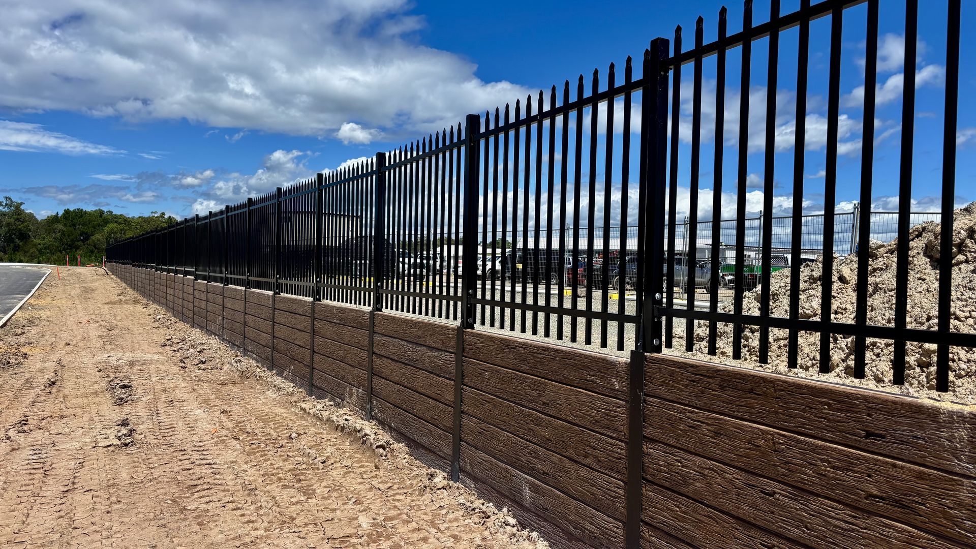 Black palisade fencing on timber sleeper retaining wall