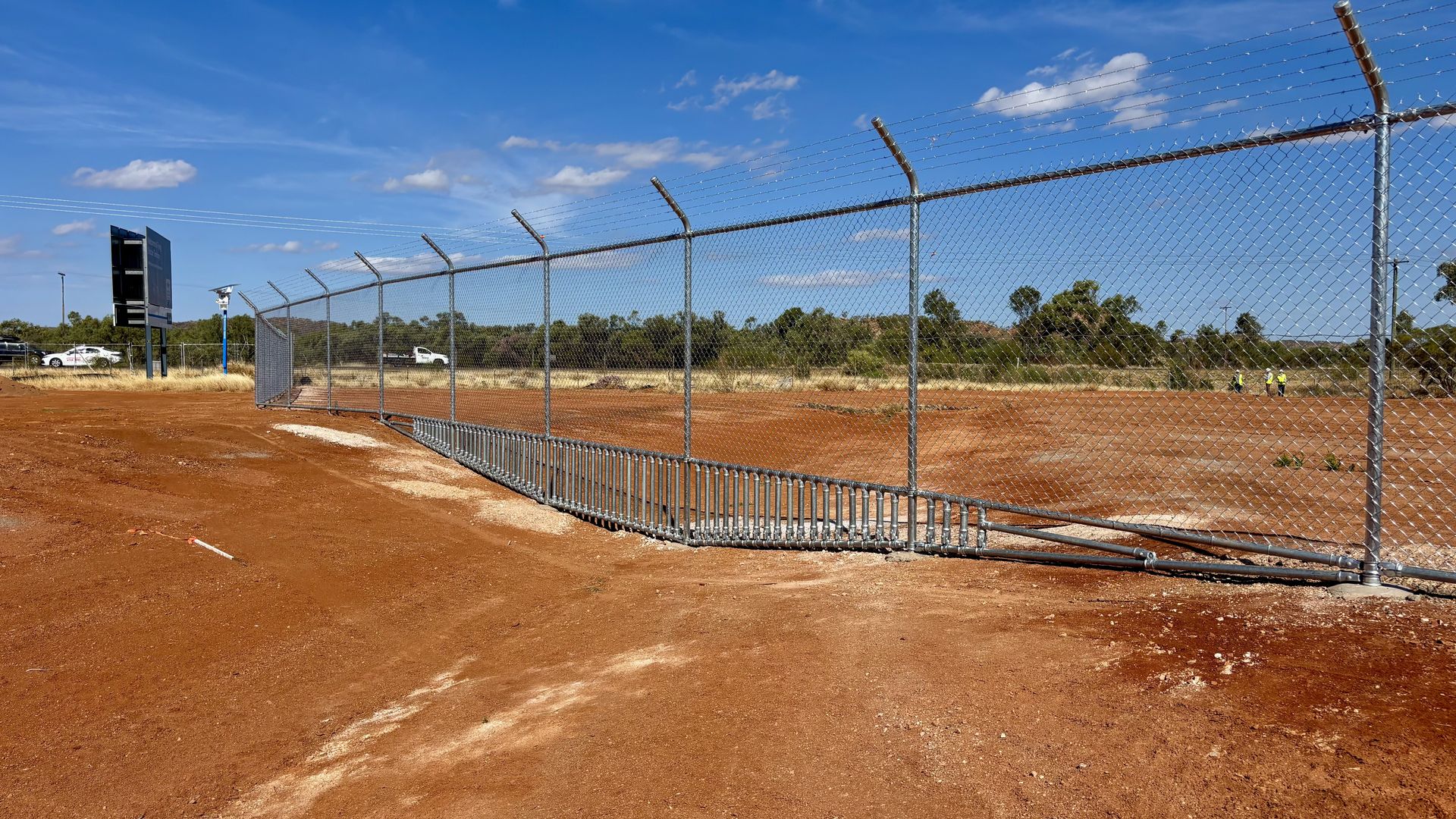 Chain wire fencing with barbed wire on red earth
