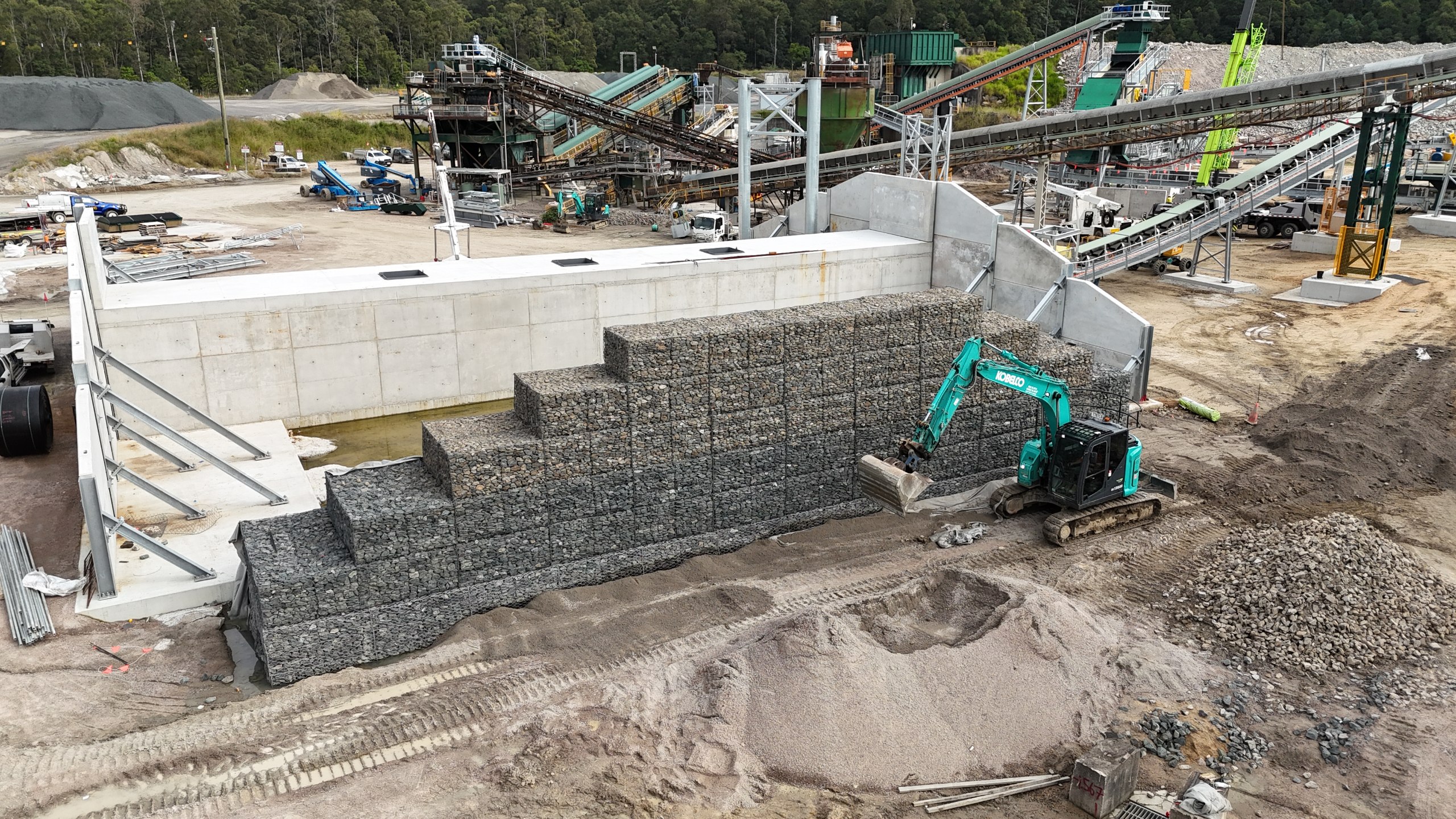 Massive gabion retaining wall aerial view with red earth and bushland
