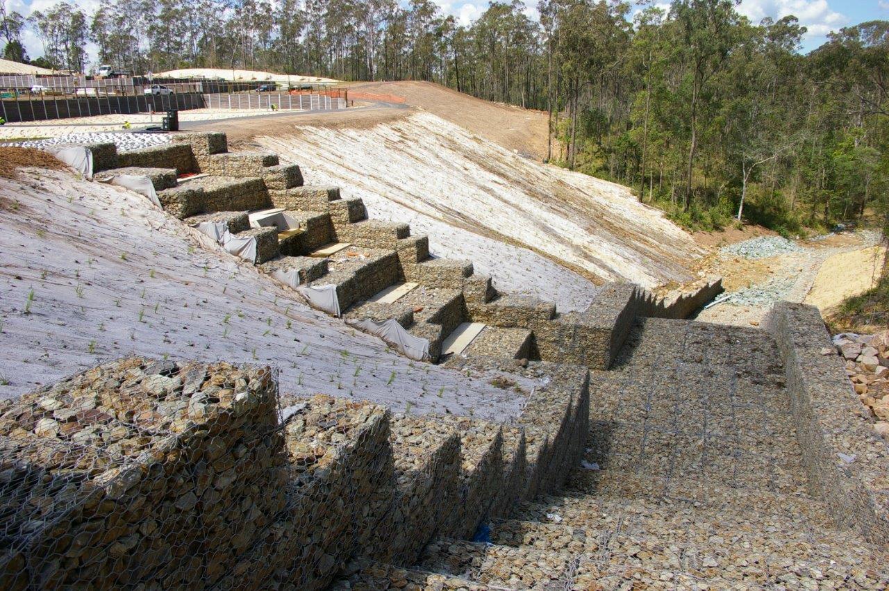 Massive gabion retaining wall aerial view with red earth and bushland