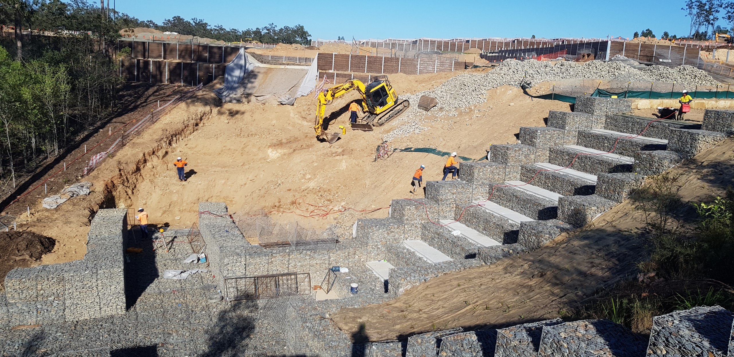 Massive gabion retaining wall aerial view with red earth and bushland