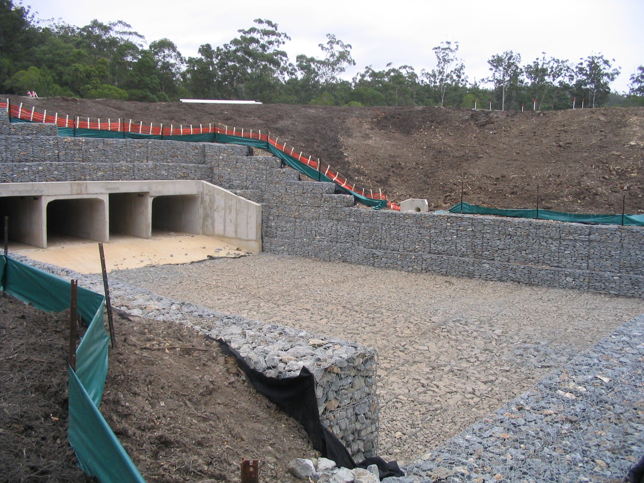 Massive gabion retaining wall aerial view with red earth and bushland