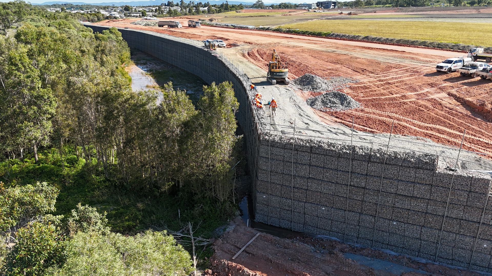Massive gabion retaining wall aerial view with red earth and bushland