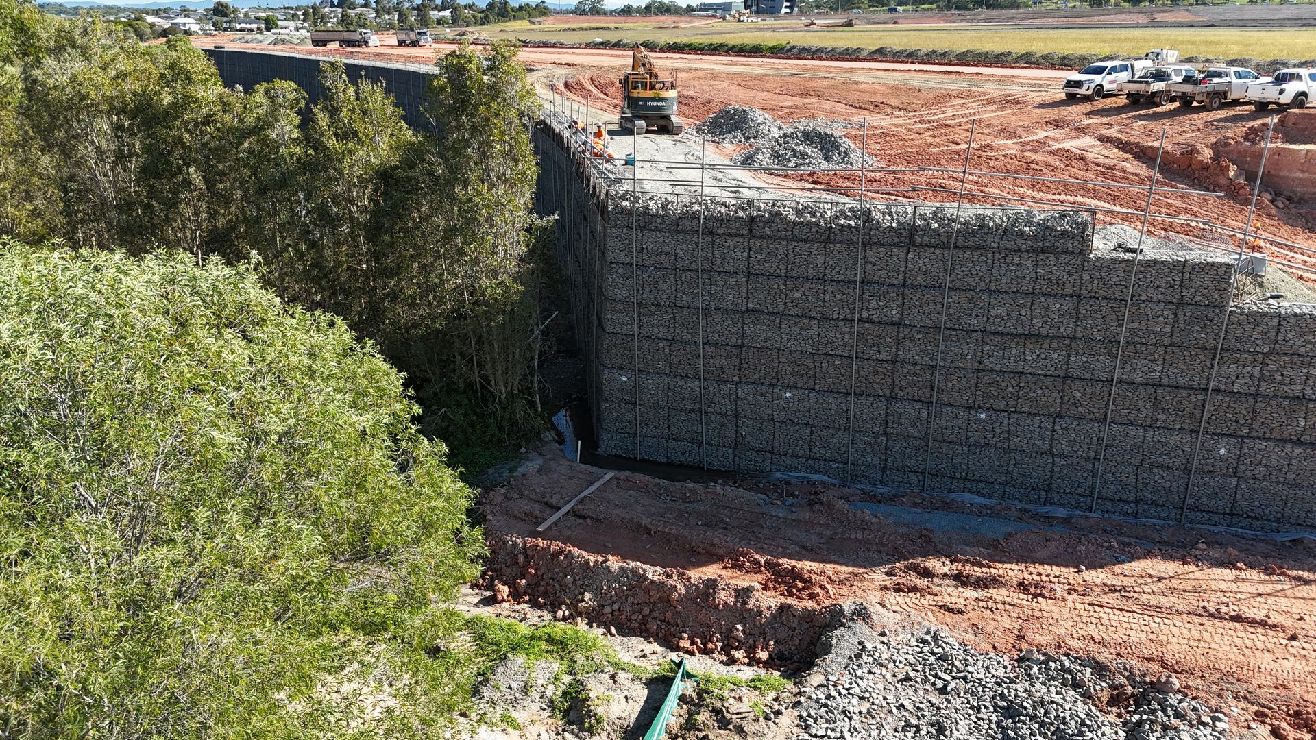 Massive gabion retaining wall aerial view with red earth and bushland